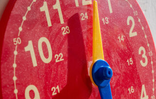 Eine rote Uhr hängt an einer Wand und zeigt Zahlen in großen Zeichen