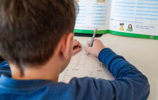 Kind schreibt Wörter in ein Heft