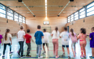 Kinder rennen in einer Reihe durch die Sporthalle 1