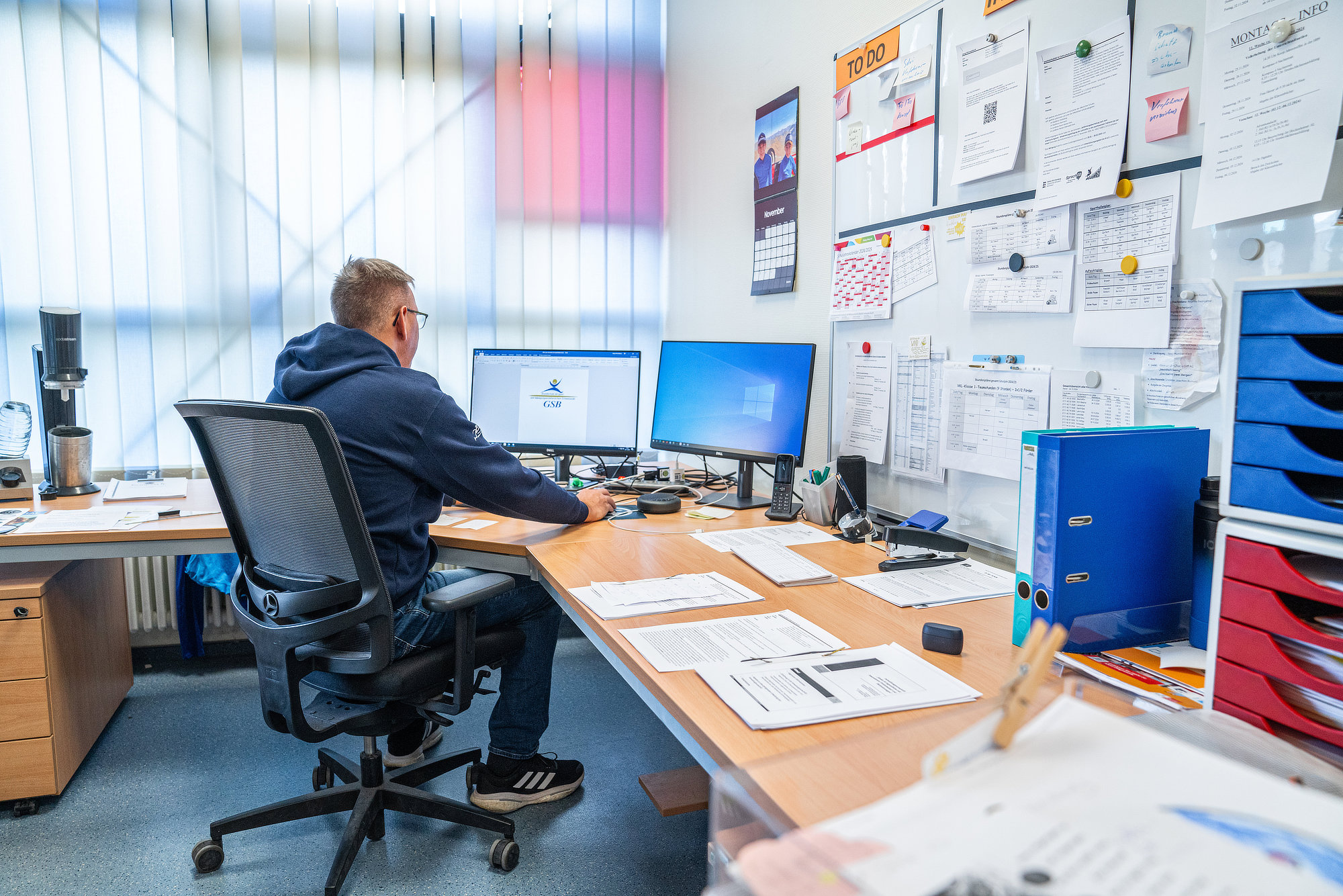 Rektor Himmelsbach arbeitet am Schreibtisch mit vielen Papieren und grossem Whiteboard