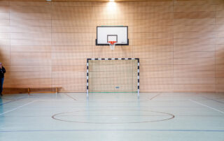 Tor und Basketballkorb von vorne in der Sporthalle